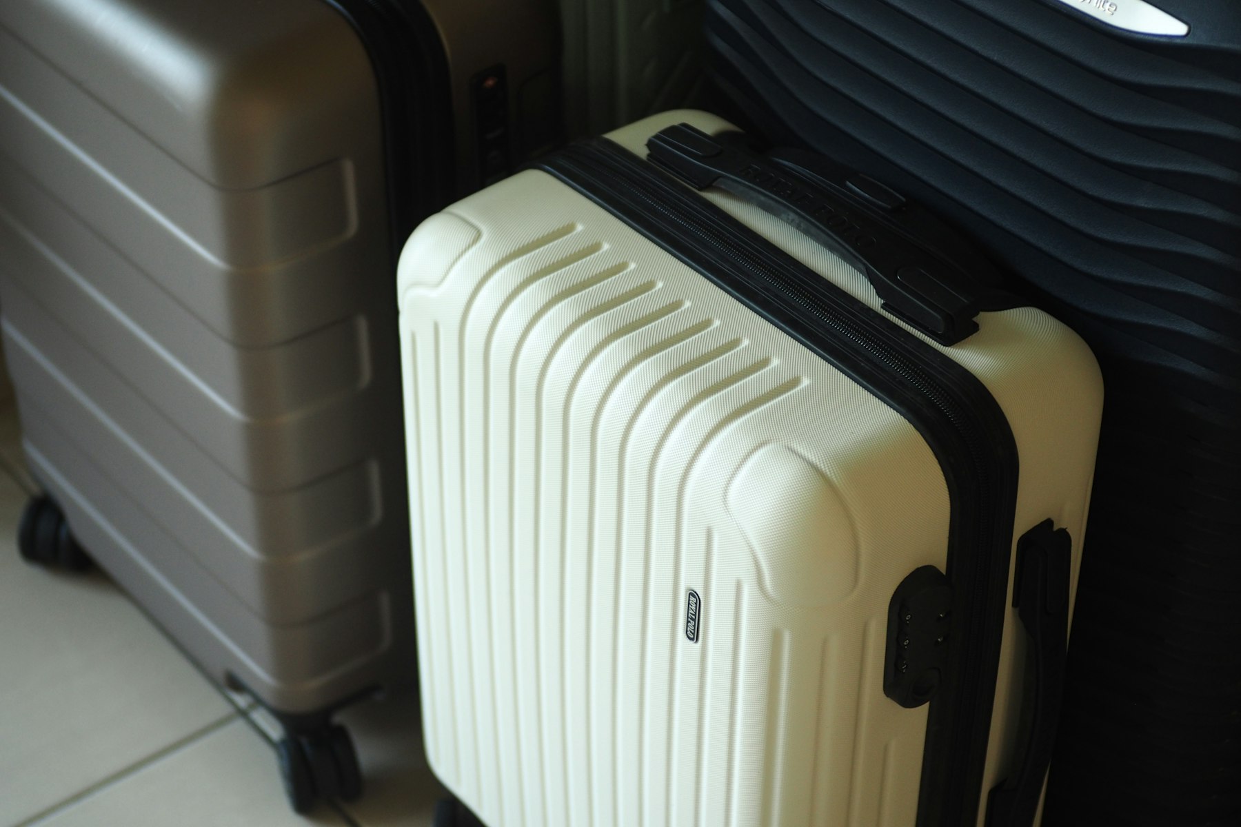 Valise cabine rigide à quatre roulettes posée au sol, poignée télescopique sortie