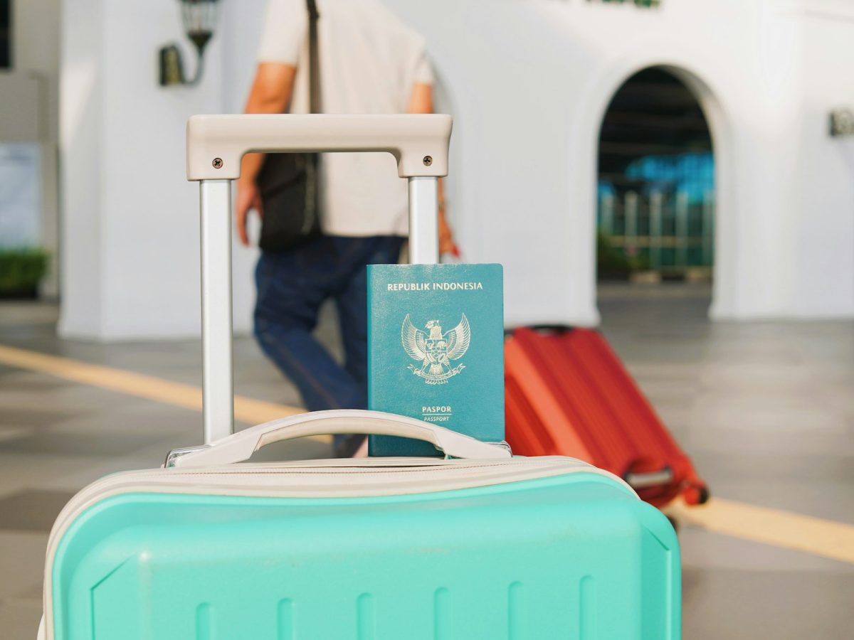Valise cabine rigide avec roulettes posée devant un comptoir d'embarquement d'aéroport