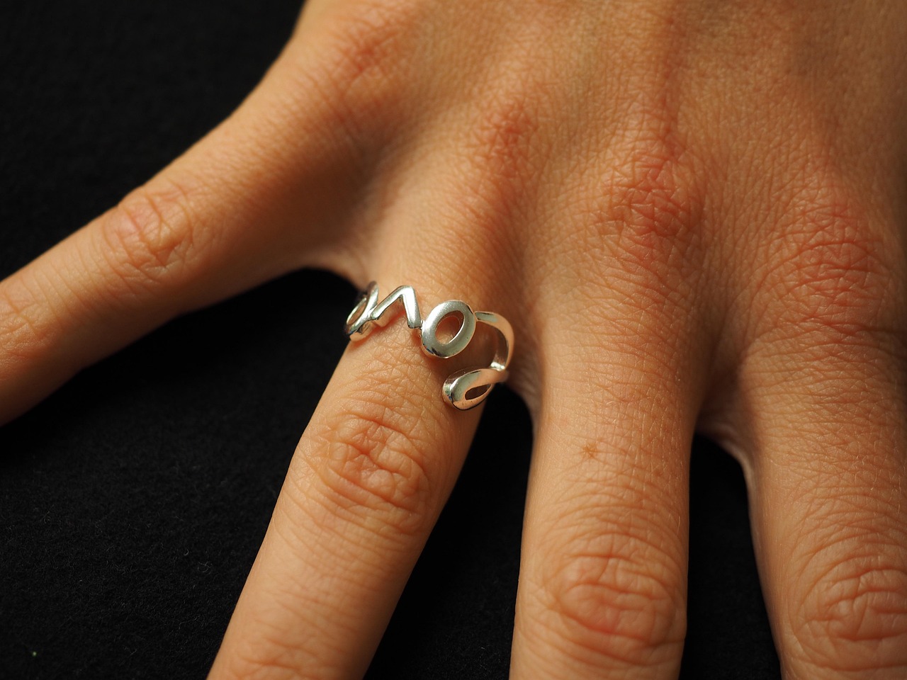 main féminine portant une bague fine, mesurée avec un baguier en métal