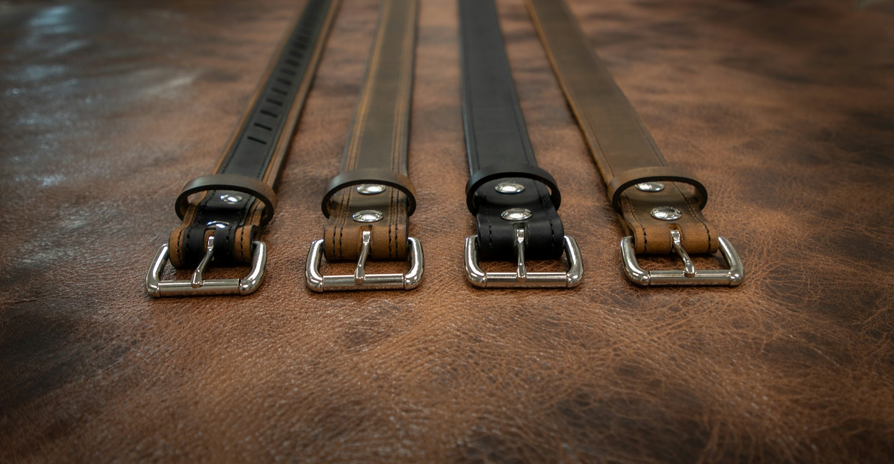 Gros plan sur une ceinture homme en cuir pleine fleur marron, grain naturel visible, bouclée avec un ardillon métallique