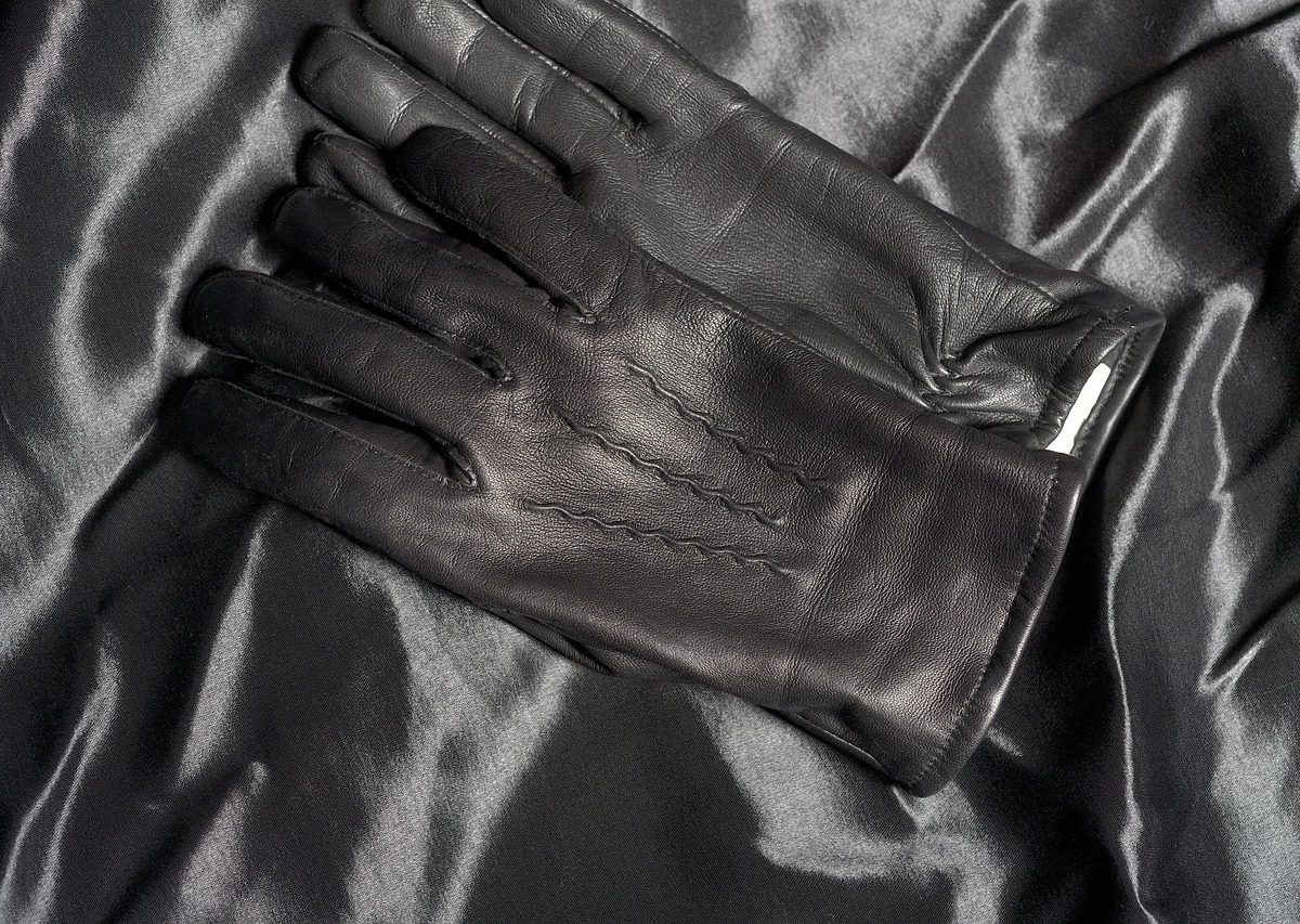 Paire de gants en cuir marron posés pliés l'un sur l'autre sur un fond neutre