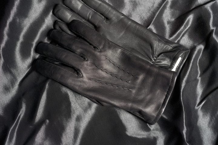 Paire de gants en cuir marron posés pliés l'un sur l'autre sur un fond neutre