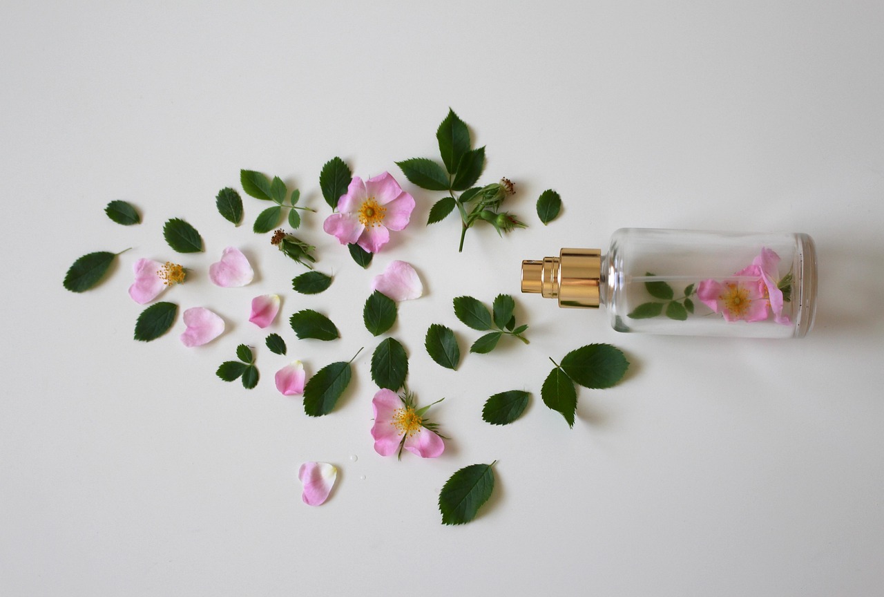 Flacon de parfum femme doré posé sur un fond clair à côté de fleurs fraîches