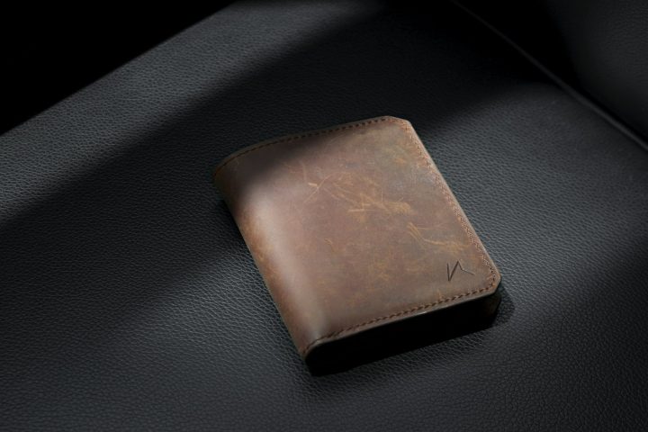 Portefeuille homme en cuir brun pleine fleur fermé posé sur une table en bois