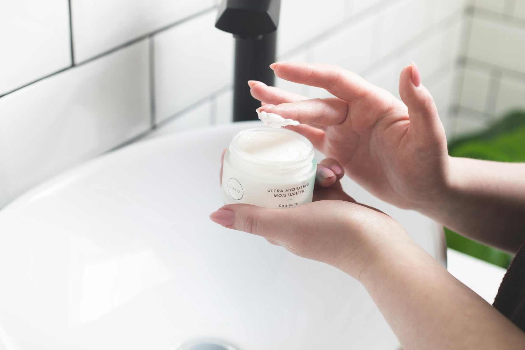 Main appliquant une crème hydratante du bout des doigts sur une joue